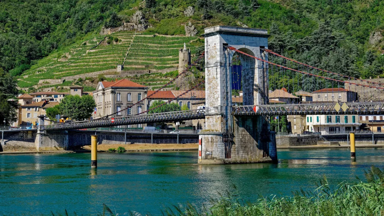 The old suspension bridge at Tournon-sur-Rhône with vineyards rising behind